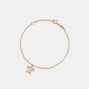 Gold bracelet with a turtle charm on a light gray background