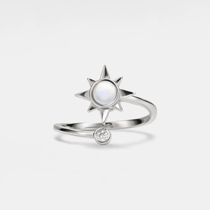 A silver-colored spinner ring featuring a central opal stone with a star design, accompanied by a small cubic zirconia.