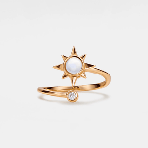 A rose gold-colored spinner ring featuring a central opal stone with a star design, accompanied by a small cubic zirconia.