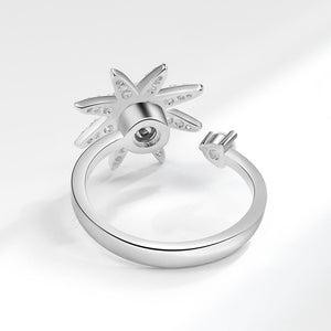 Silver sun-shaped spinner ring with gemstones on a light gray background