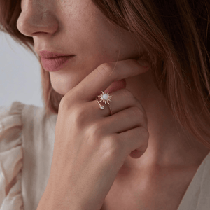 Close up model image wearing a gold spinner ring with opal sun design and small gemstone