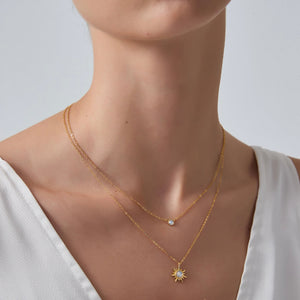 Close-up of a person wearing a gold necklace with a star-shaped pendant on a plain background