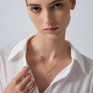 Woman wearing a gold necklace with a white shirt on a plain background