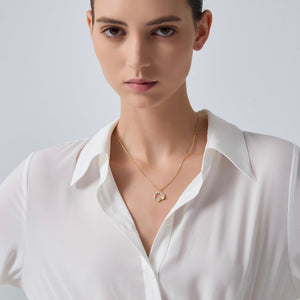 Woman wearing a gold necklace with a white shirt on a plain background