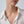 Gold necklace with a pendant worn by a person in a white shirt against a neutral background