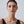 Woman wearing gold hoop earrings against a plain background