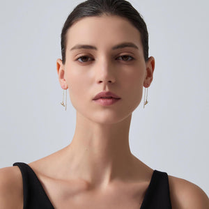 Woman wearing gold hoop earrings against a plain background