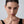 Woman wearing gold earrings with a neutral background