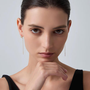 Woman wearing gold earrings with a neutral background