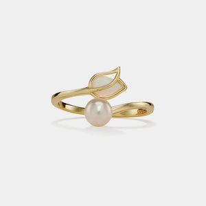 Gold ring with a pearl and leaf design on a light gray background