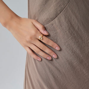 Hand wearing a pearl ring on a neutral background
