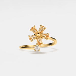 Gold ring with a star-shaped gemstone and smaller round gemstone on a light gray background