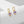 A pair of oval cut amethyst drop hoop earrings, one plated in silver and the other in gold, displayed against a neutral background.