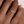 Rose gold ring with a diamond on a hand against a neutral background