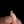 Gold ring with a diamond held between fingers against a black background