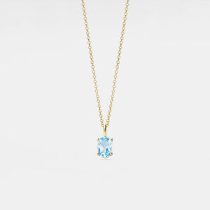 Gold necklace with a blue gemstone pendant on a light gray background