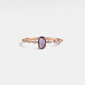 An oval cut natural amethyst ring with gold plating, set on a silver band and displayed against a white background.