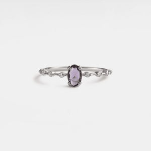 An oval cut natural amethyst ring with gold plating, set on a silver band and displayed against a white background.