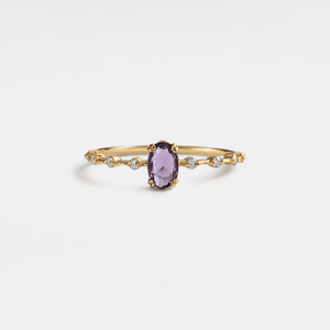 Gold ring with a purple gemstone on a white background