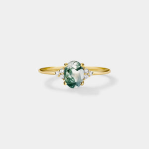 Gold ring with a green gemstone on a light gray background