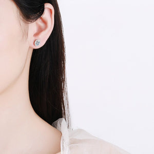Close-up of a person wearing a diamond earring on a plain background