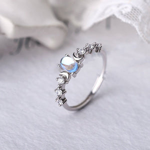Silver ring with a central blue gemstone on a white fabric background