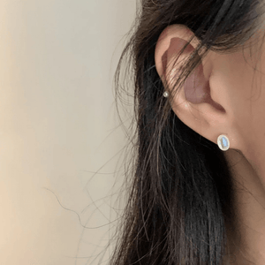 Close-up of an ear wearing a small earring with a blurred background