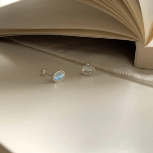 Pair of silver earrings with gemstones on a beige surface