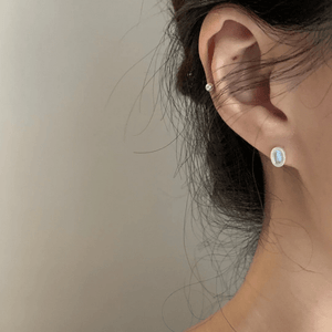 Close-up of an ear wearing a small earring with a blurred background