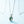Silver necklace with a green pendant on a light blue background