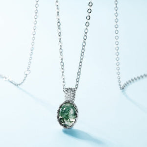 Silver necklace with a green pendant on a light blue background