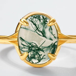 Gold ring with a green moss stone on a white background
