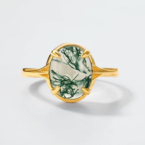 Gold ring with a green stone on a light gray background