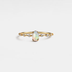 Gold ring with an opal stone on a light gray background