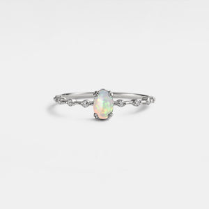 Silver ring with a central opal stone on a light gray background
