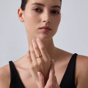 Woman wearing a ring with a diamond on a plain background