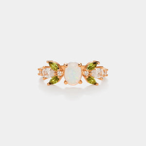 Gold earring with opal and green gemstones on a light gray background