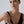 Woman wearing a black top and a ring on her finger against a plain background