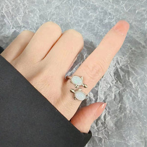 Model wearing a silver turtle-shaped ring with opal stones and 'I love you forever' engraving on a white background