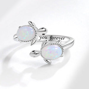 Silver turtle-shaped ring with opal stones and 'I love you forever' engraving on a white background