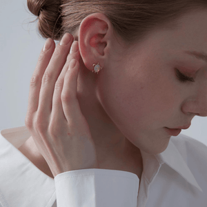Women wearing opal sea turtle earrings with gold accents on a light gray background