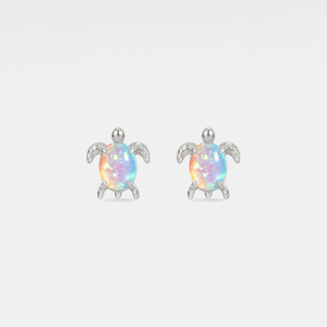 Opal sea turtle earrings with silver accents on a light gray background