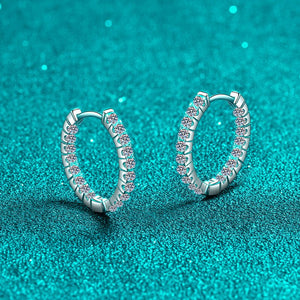 Silver hoop earrings with small diamonds on a teal glitter background