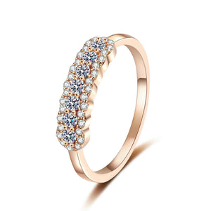 Rose gold ring with moissanite accents on a white background