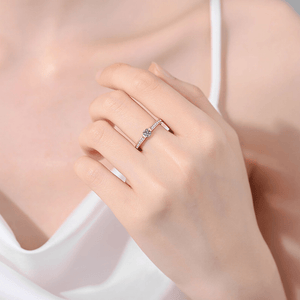 Close-up of a hand wearing a silver ring with a blue gemstone on a soft pink background