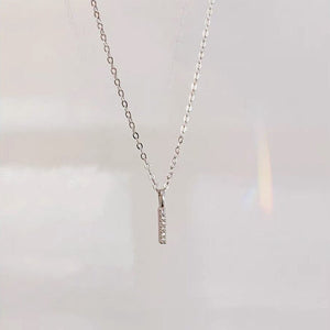 A gold-plated sterling silver bar pendant necklace with cubic zirconia, displayed on a black background.