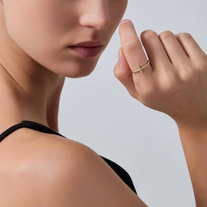 Woman wearing a gold ring on her finger against a neutral background