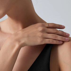 Close-up of a person's hand with a gold ring on a neutral background