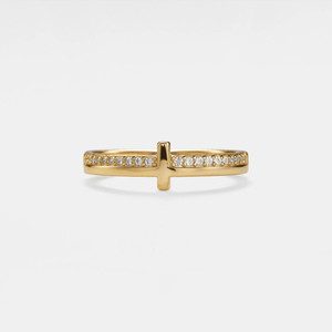 Gold ring with a cross design and small diamonds on a light gray background