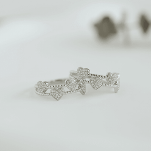 Silver ring with heart designs on a light gray background